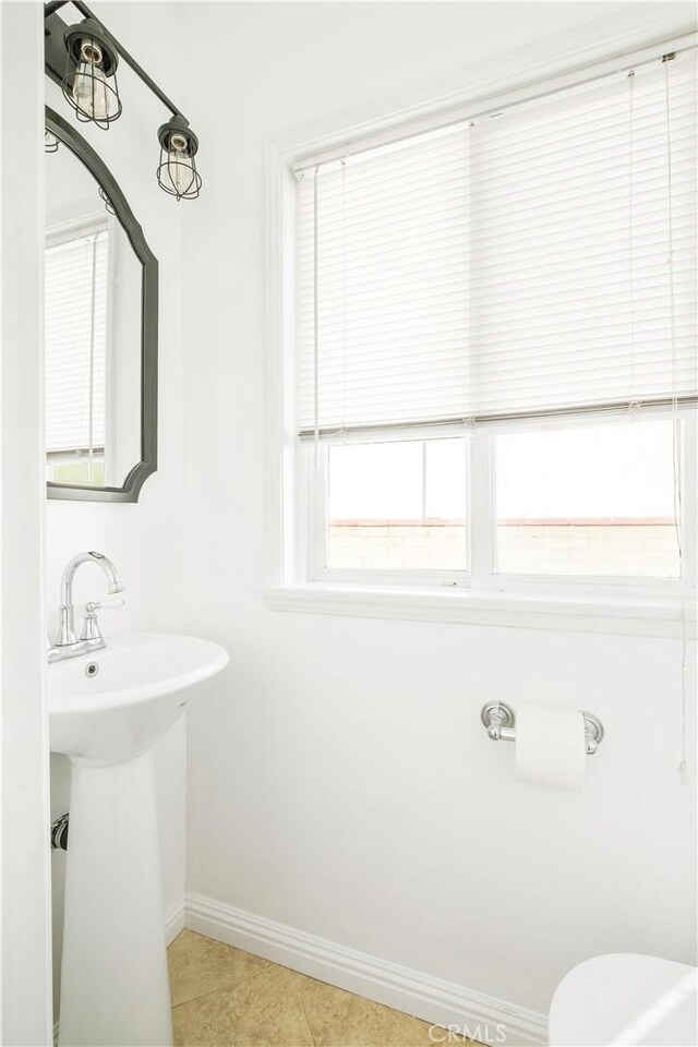 half bathroom featuring a sink, baseboards, and tile patterned floors