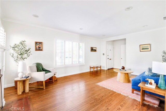 sitting room featuring ornamental molding, baseboards, and wood finished floors