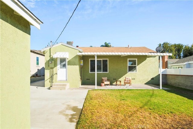 rear view of property featuring a patio area, a yard, fence, and stucco siding