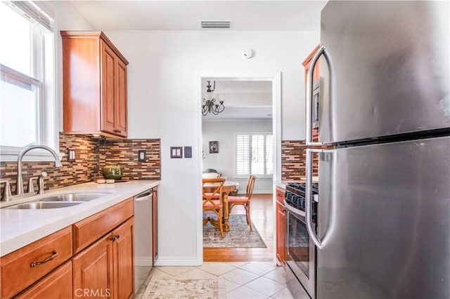 kitchen with light tile patterned floors, sink, appliances with stainless steel finishes, and tasteful backsplash