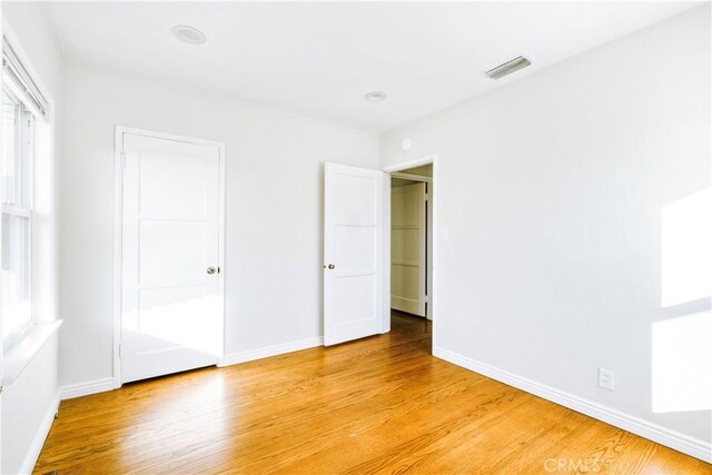 unfurnished bedroom featuring light wood-type flooring, baseboards, and visible vents