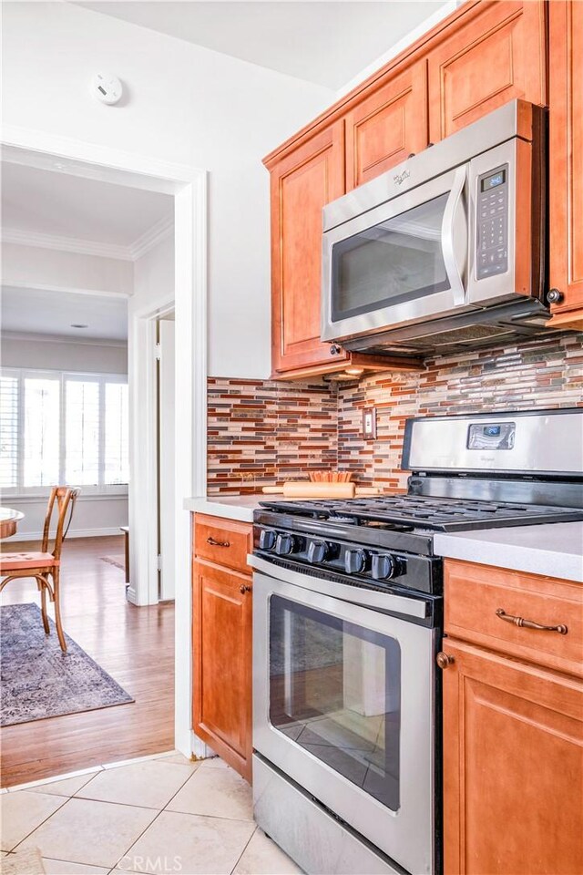 kitchen featuring light tile patterned floors, tasteful backsplash, stainless steel appliances, and light countertops