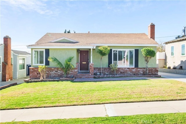 ranch-style home with brick siding, a front lawn, and stucco siding