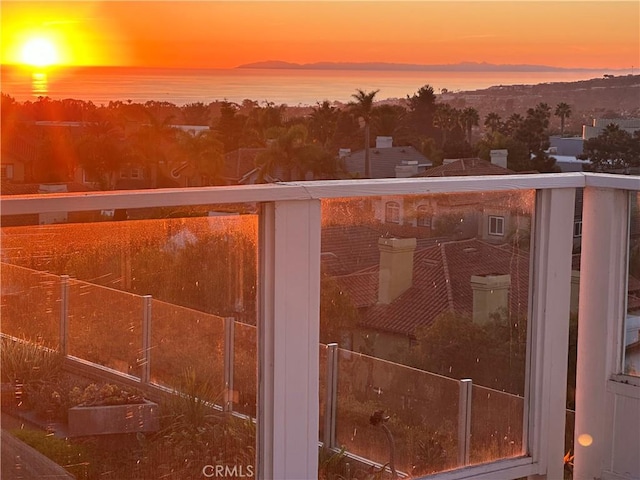 balcony at dusk featuring a water view