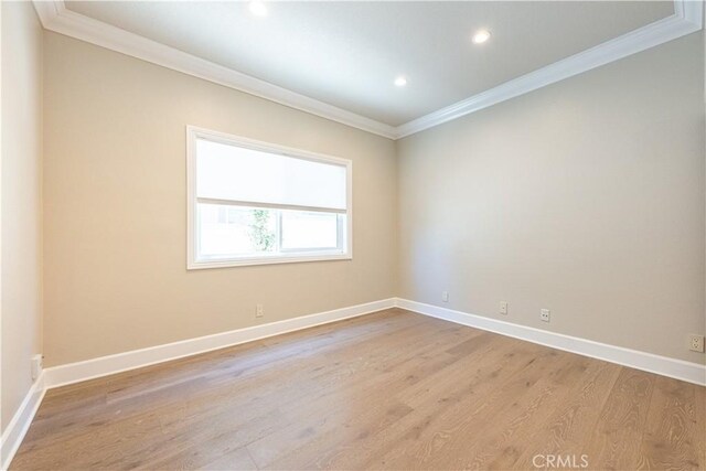 spare room with ornamental molding and light hardwood / wood-style floors