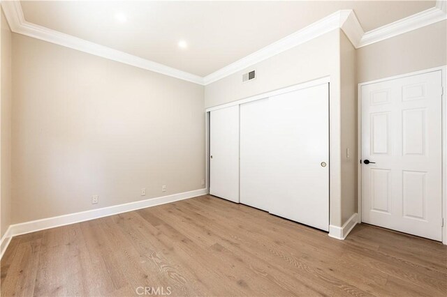 unfurnished bedroom featuring light wood-type flooring, a closet, and ornamental molding