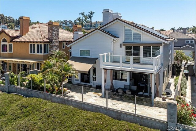 rear view of property featuring a patio area, a balcony, and a yard