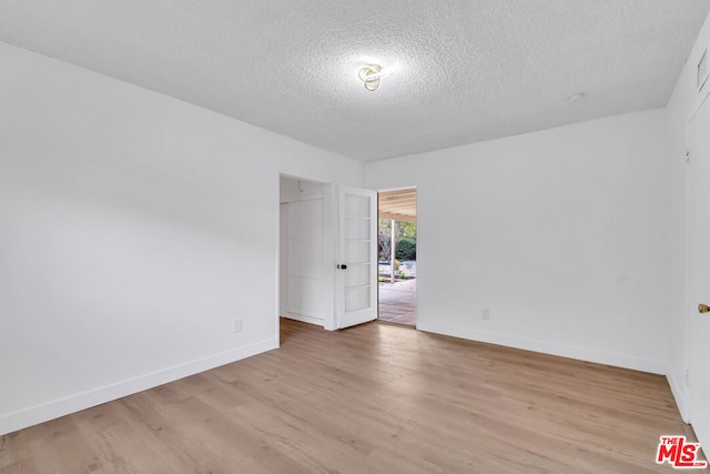 unfurnished room with light hardwood / wood-style floors and a textured ceiling