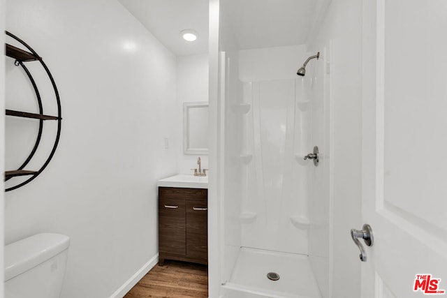 bathroom with toilet, a shower, hardwood / wood-style floors, and vanity