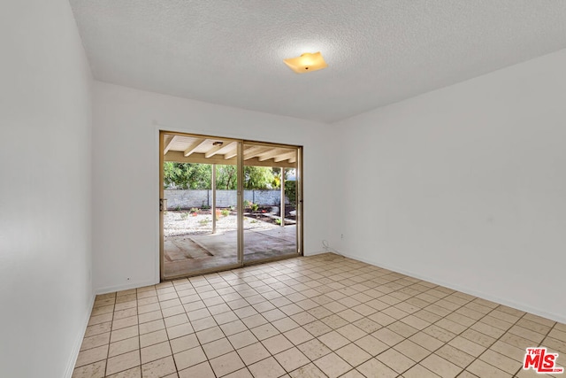 tiled empty room with a textured ceiling