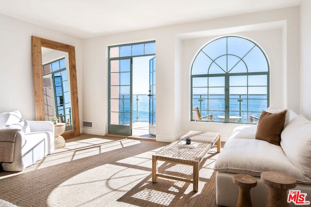 living area with light carpet and a water view