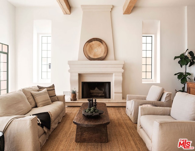 living room with a healthy amount of sunlight, beam ceiling, and a fireplace