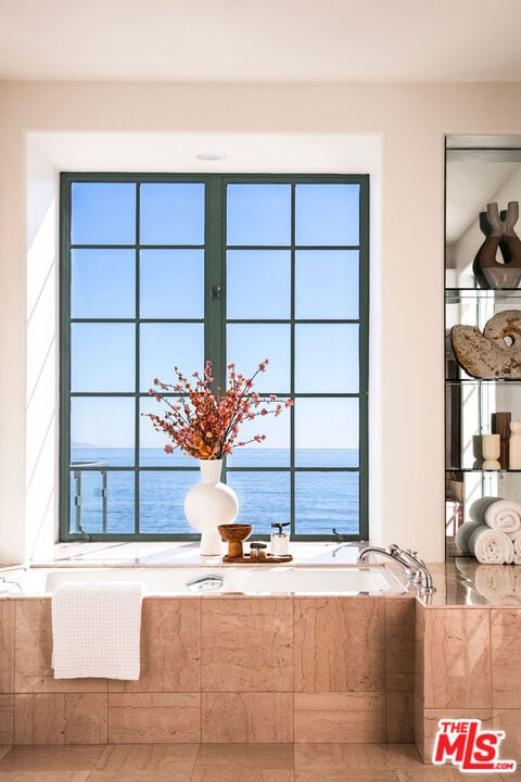 interior details featuring tiled bath and a water view