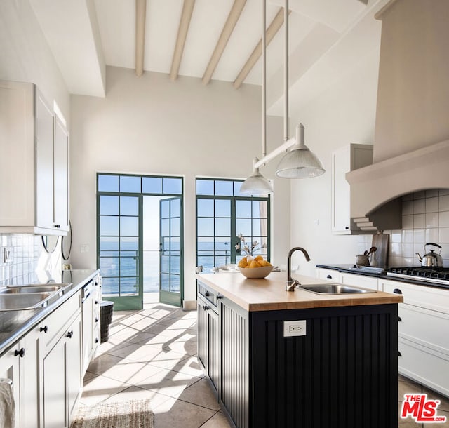 kitchen with white cabinetry, sink, a water view, and a kitchen island with sink