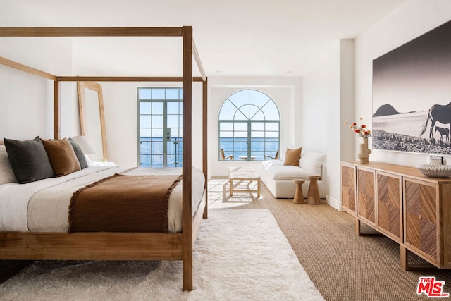 bedroom featuring carpet floors, french doors, and a water view