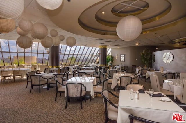 carpeted dining area with a raised ceiling