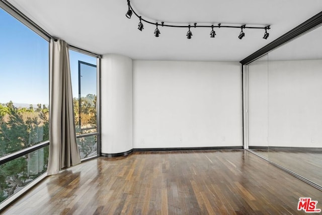 spare room with dark wood-type flooring, expansive windows, and track lighting