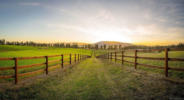 yard at dusk featuring a rural view and a mountain view