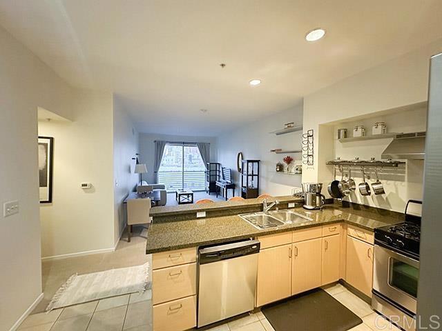 kitchen with appliances with stainless steel finishes, extractor fan, sink, kitchen peninsula, and light tile patterned floors