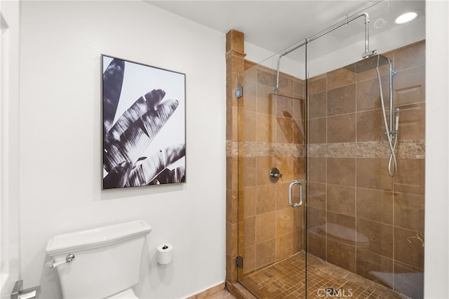 bathroom featuring toilet and a shower with shower door