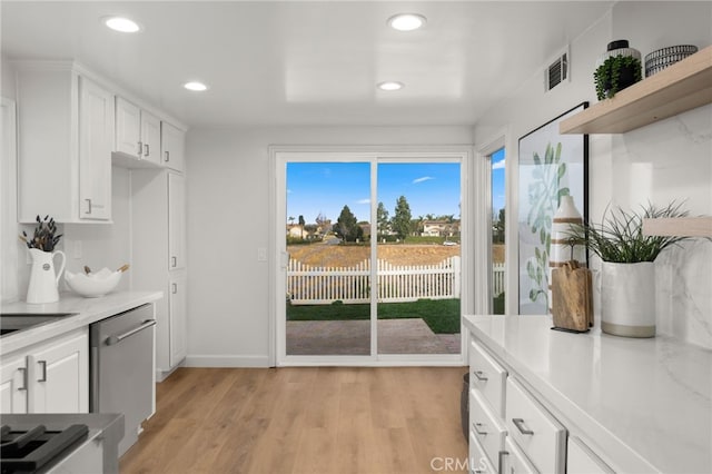 kitchen featuring light stone counters, white cabinetry, dishwasher, and light hardwood / wood-style flooring