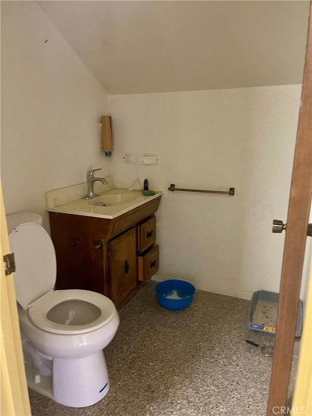 bathroom featuring toilet, vanity, and lofted ceiling