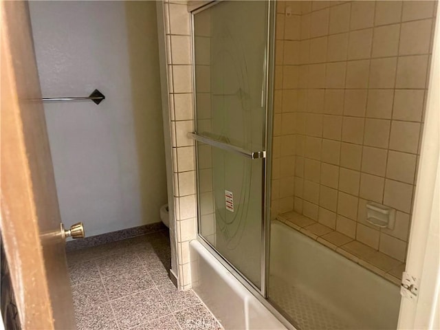 bathroom with toilet and bath / shower combo with glass door