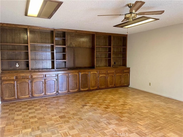 unfurnished living room with a textured ceiling, ceiling fan, and light parquet flooring