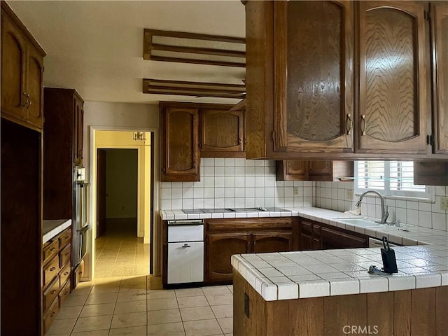 kitchen with sink, backsplash, tile countertops, light tile patterned floors, and black electric cooktop