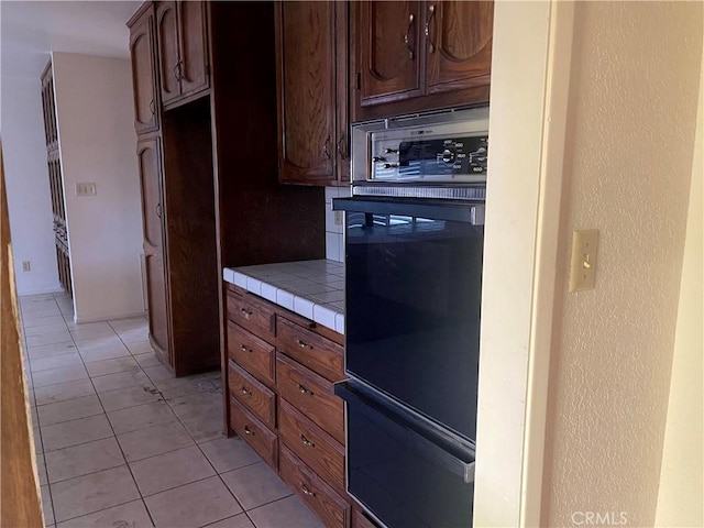 kitchen featuring light tile patterned floors, oven, and tile countertops