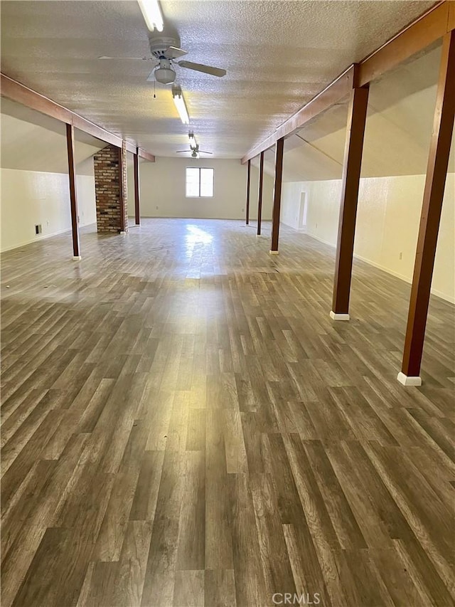 basement featuring a textured ceiling, ceiling fan, and dark hardwood / wood-style floors