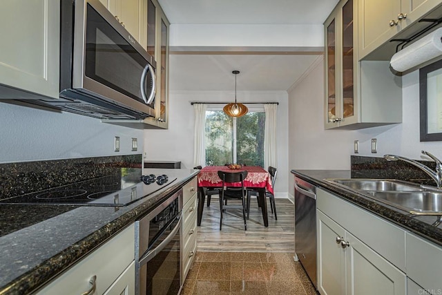 kitchen with stainless steel appliances, decorative light fixtures, sink, and dark stone countertops