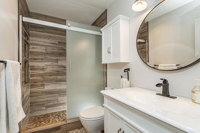 bathroom featuring vanity, toilet, and a tile shower