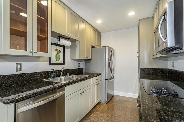 kitchen with appliances with stainless steel finishes, sink, and dark stone counters