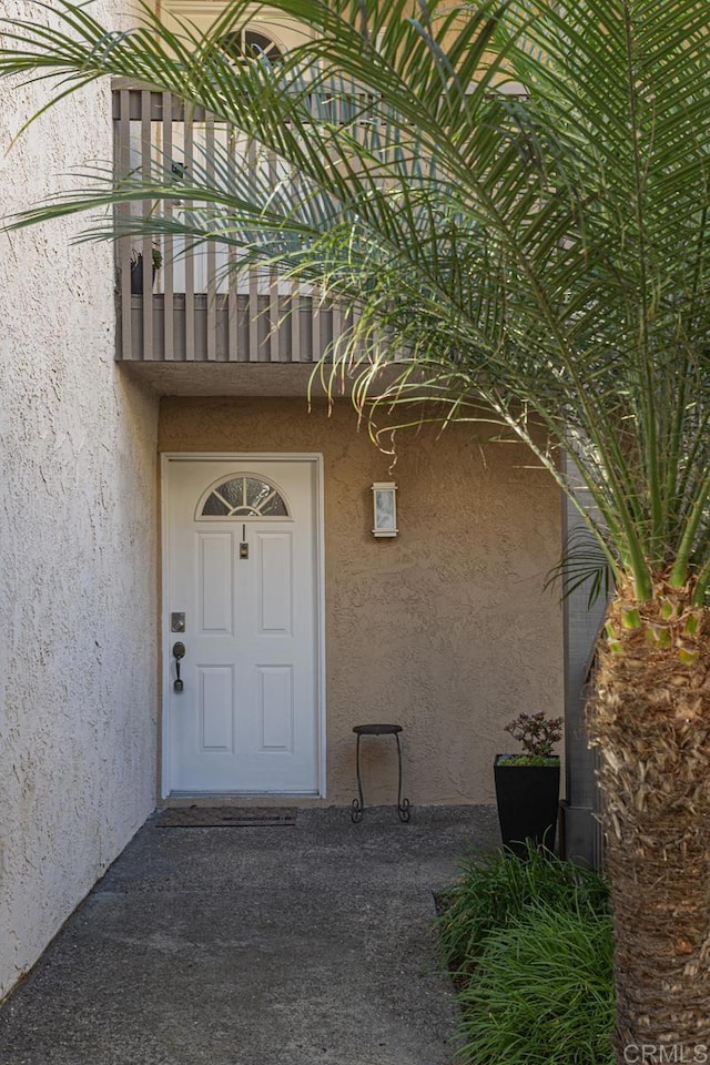 property entrance with a balcony and stucco siding