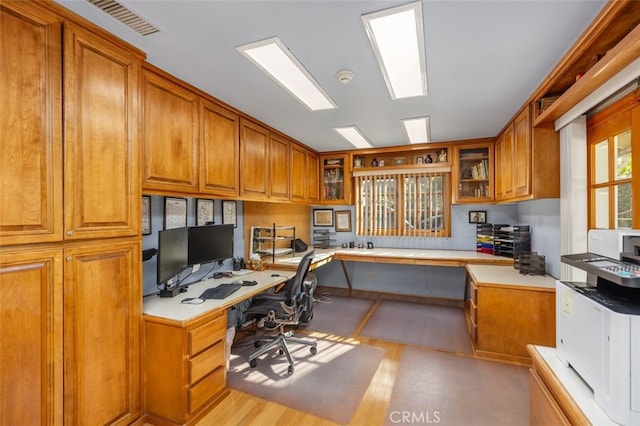 home office with built in desk and light hardwood / wood-style flooring