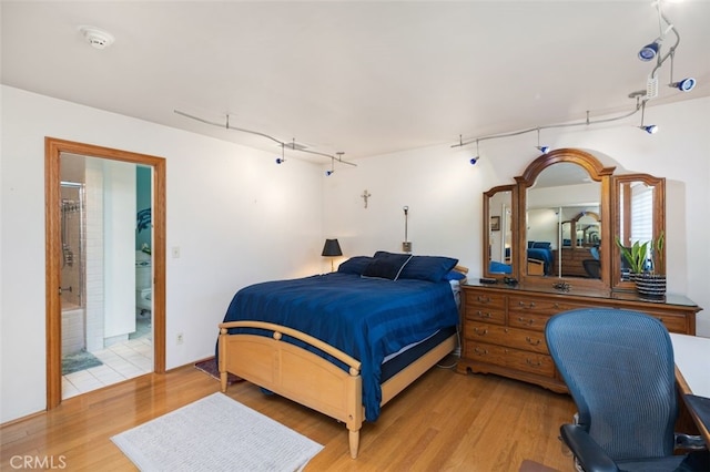 bedroom with ensuite bath and hardwood / wood-style floors