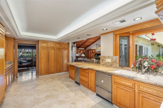 kitchen with light stone countertops, sink, dishwasher, and kitchen peninsula