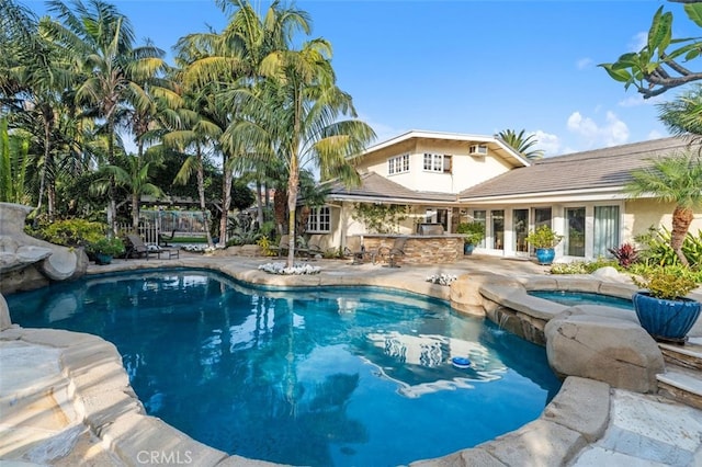 view of swimming pool featuring an in ground hot tub, an outdoor bar, exterior kitchen, and a patio