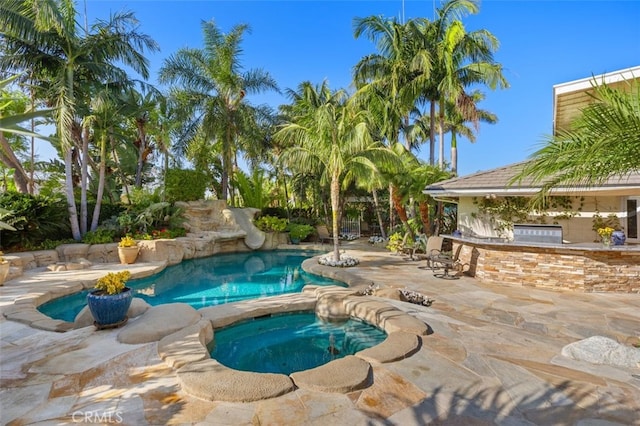 view of swimming pool with an outdoor kitchen, a patio, and an in ground hot tub