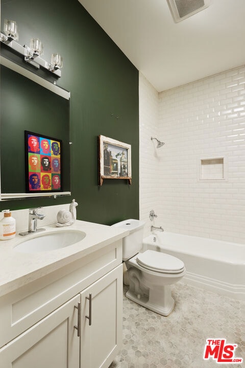 full bathroom with toilet, tiled shower / bath combo, and vanity