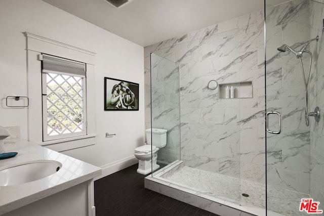 bathroom with toilet, a shower with shower door, and vanity