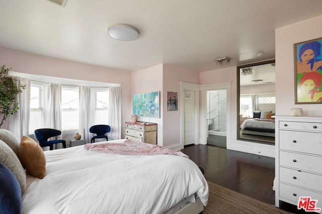 bedroom featuring dark wood-type flooring, multiple windows, and connected bathroom