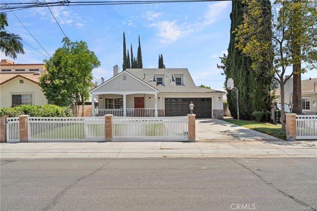 view of front of house featuring a fenced front yard, concrete driveway, covered porch, and a garage