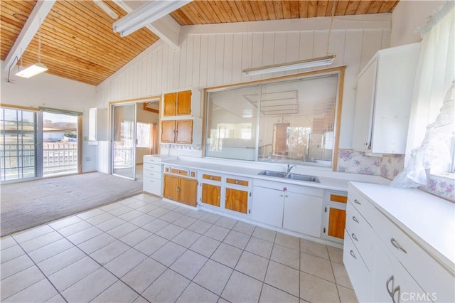 kitchen with lofted ceiling with beams, sink, light colored carpet, and white cabinets