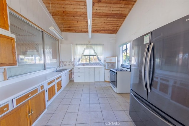 kitchen featuring lofted ceiling with beams, light tile patterned floors, fridge, wooden ceiling, and white gas range