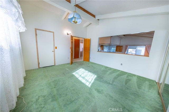 unfurnished living room with high vaulted ceiling, light colored carpet, and beam ceiling