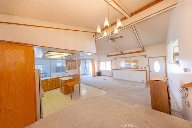 kitchen with pendant lighting, vaulted ceiling with beams, light colored carpet, and an inviting chandelier