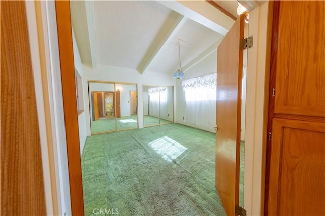 unfurnished room with carpet floors and vaulted ceiling with beams