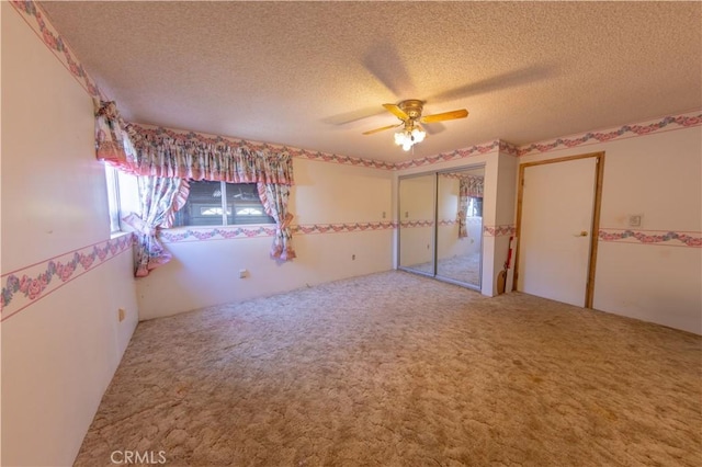 unfurnished bedroom with carpet flooring, a textured ceiling, ceiling fan, and a closet